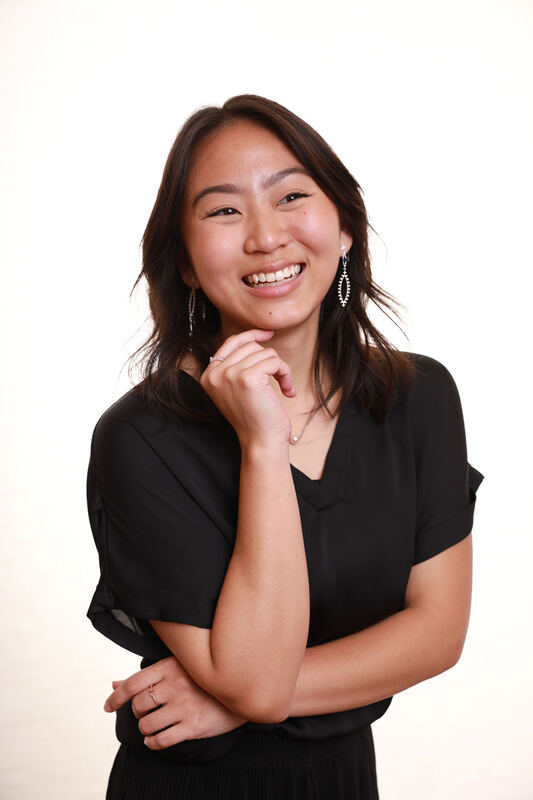 Aileen Mae Sze smiling in a black shirt against a white backdrop