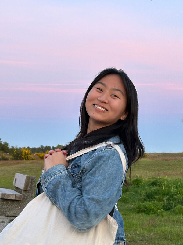 Aileen Mae Sze outdoors at golden hour in a denim jacket, smiling at the camera