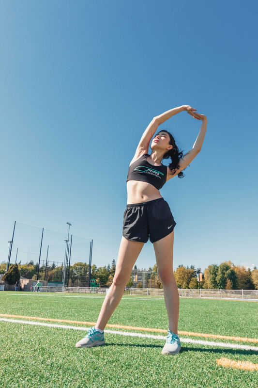 An athlete stretching on an outdoor turf field under a blue sky