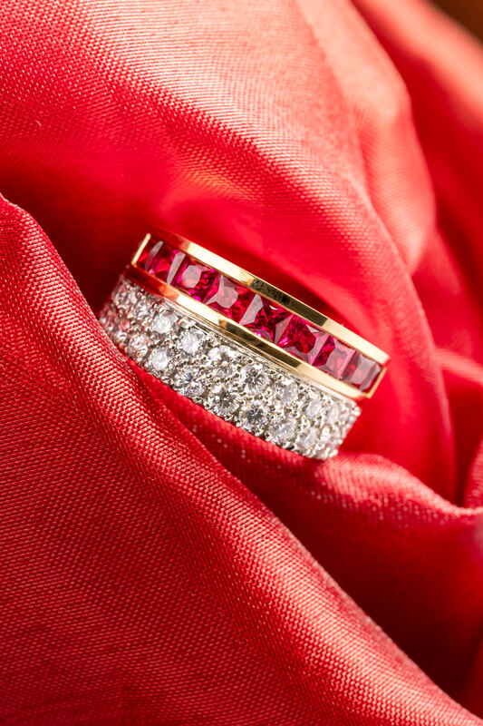 A ruby and diamond band resting on folds of red silk