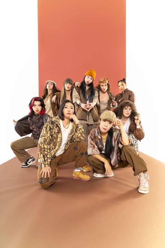 Diamonds Crew dancers posed in a tight group on a terracotta studio backdrop