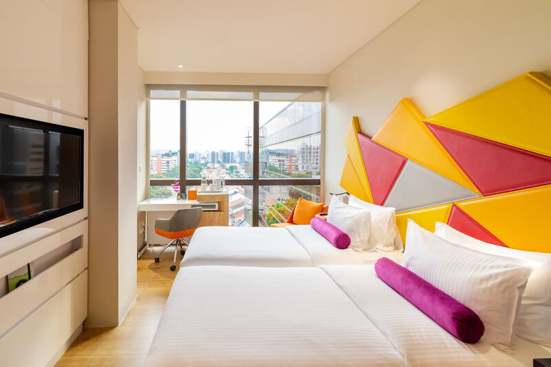 Ibis Styles hotel room with a bright yellow and pink geometric headboard