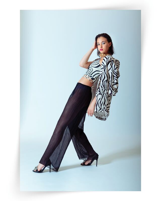A model in zebra-print jacket and sheer trousers posing on a pale blue backdrop, published in Vigour Magazine