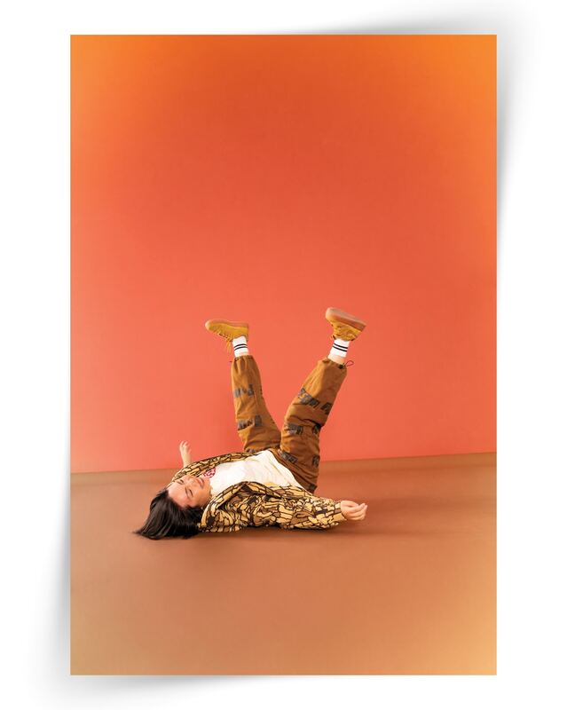 A dancer mid-fall upside down on a warm orange backdrop, an unplanned moment
