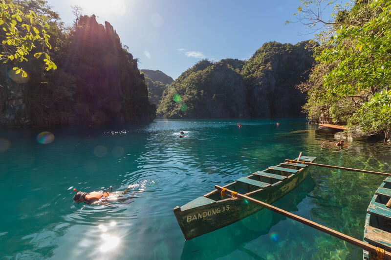 Turquoise water and limestone cliffs at Kayangan Lake, Coron, with a swimmer