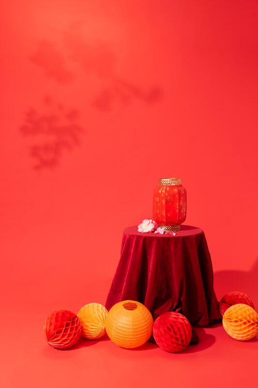 A red still life with a gold jar, red cloth, and paper lanterns for Lunar New Year