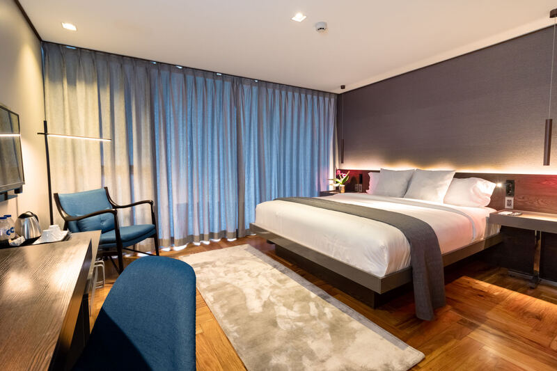 Ramada Encore Makati hotel room with a blue armchair and soft lighting