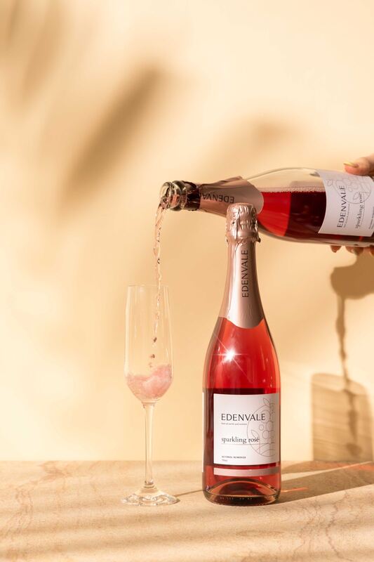 A bottle of Edenvale sparkling rosé pouring into a flute against warm light