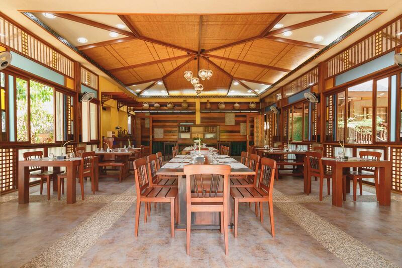 The dining hall at Sophia's Garden Resort with timber beams and wooden chairs