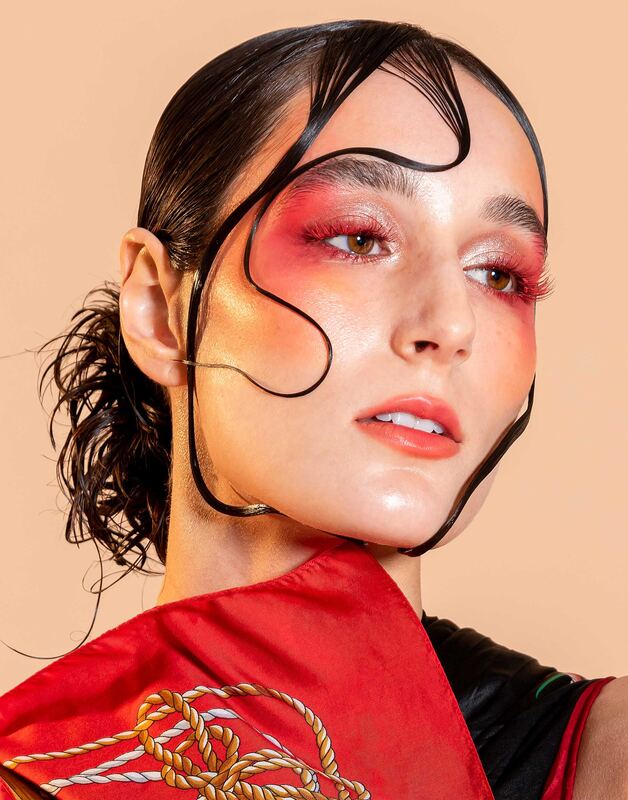 Close beauty portrait with ink-like hair curls and red eye makeup